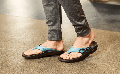 Person wearing blue sandals on a neutral background
