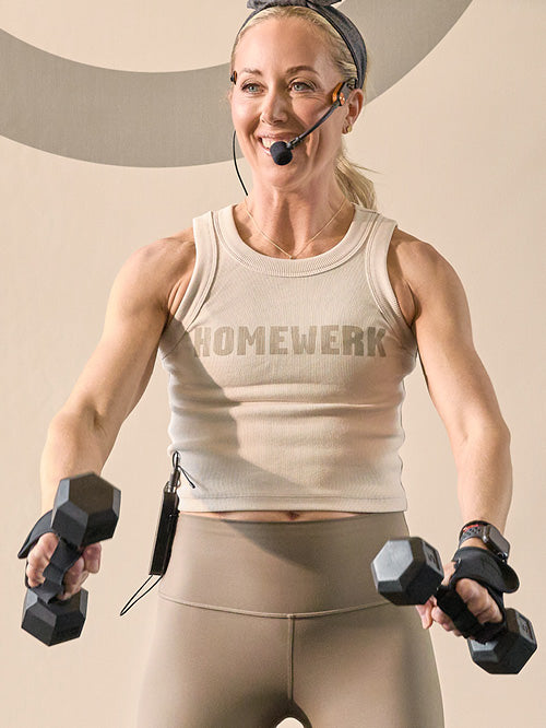 Woman exercising with dumbbells wearing a 'HOMEMWERK' tank top against a neutral background