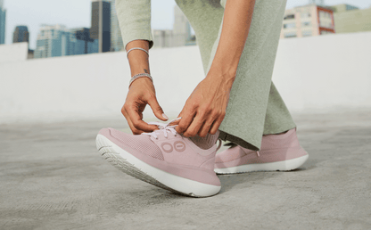 Women's OOmy Stride - Stardust model outside adjusting shoe lace | lifestyle