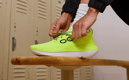 Men's OOmy Stride - Electro model trying shoe on bench in locker room | lifestyle