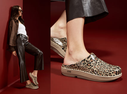 A split-view fashion photo showing a model wearing leopard-print clogs and a matching pair of clogs, with a close-up of the shoe on the right and a full-body pose on the left. The model wears black leather pants and a white top against a deep red studio background.