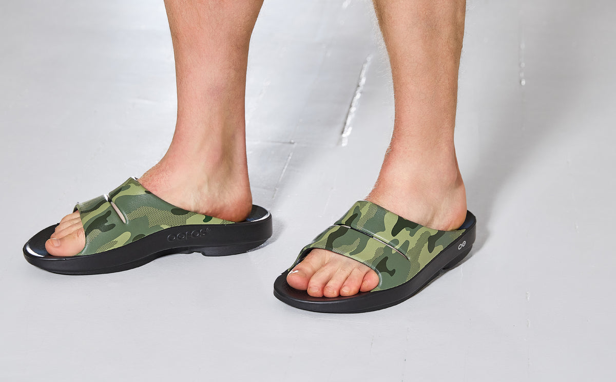 Green camouflage sandals worn by a person on a white background | lifestyle