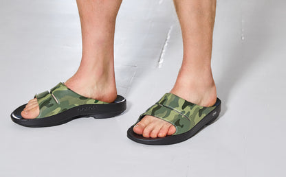 Green camouflage sandals worn by a person on a white background | lifestyle