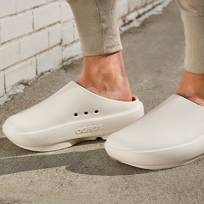 Chalk clogs worn on a concrete surface with a light-colored brick wall in the background