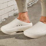 Chalk clogs worn on a concrete surface with a light-colored brick wall in the background