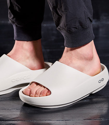 Chalk sandals worn by a person on a dark floor