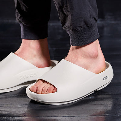Chalk sandals worn by a person on a dark floor