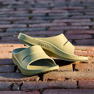 Pair of green sandals on a brick surface