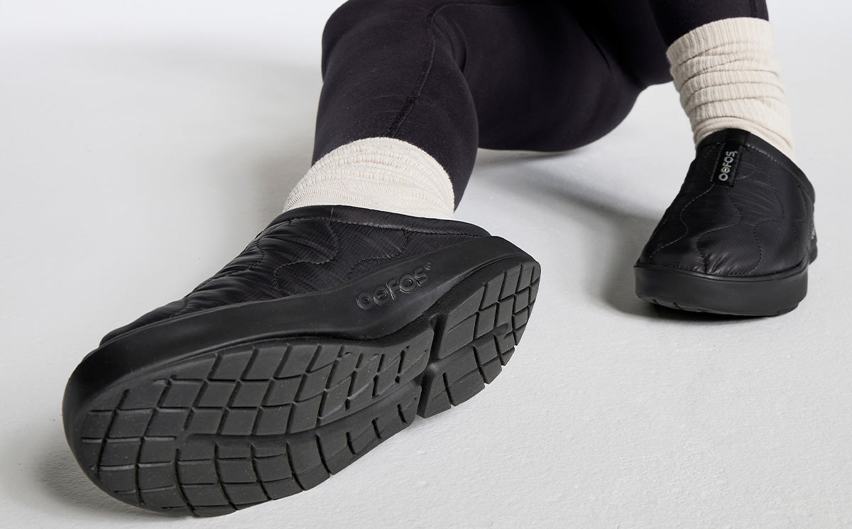 Women's OOcoozie Thermo Mule - Black close up of shoes on model sitting in studio | lifestyle