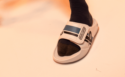 BAUER/OOFOS Men's OOahh Sport Flex Sandal – White close up of shoe on models foot in studio | lifestyle