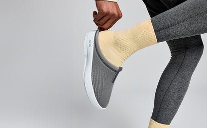 Men's OOcoozie Sport Mule - Slate model in studio adjusting back of shoe | lifestyle